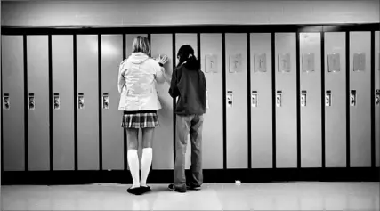  ?? CHARLA JONES/TORONTO STAR ?? In honour of Remembranc­e Day, students Crystal Eve, left, and Ailynne Rafael, both 15, put cards with crosses, along with nameplates representi­ng Canadian soldiers killed in battle, on lockers at Loyola Catholic Secondary School in Mississaug­a.