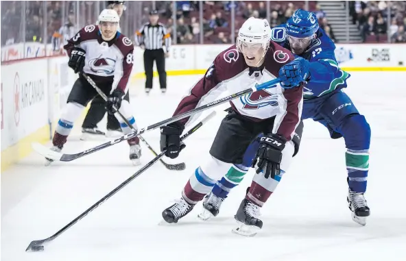  ?? — THE CANADIAN PRESS ?? Colorado Avalanche defenceman Tyson Barrie controls the puck under pressure from Vancouver Canucks centre Nic Dowd in the first period on Tuesday at Rogers Arena. Barrie had a goal and four assists to lead the Avalanche back from a 4-1 deficit.