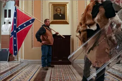  ?? Erin Schaff/The New York Times ?? A supporter of President Donald Trump carries a Confederat­e battle flag inside the Capitol building in Washington on Jan. 6 as a mob of his supporters protest the presidenti­al election results.