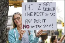  ?? JAY JANNER / AMERICAN-STATESMAN ?? Lori McClure holds a tax-bill protest sign Monday near U.S. Sen. John Cornyn’s office at West Sixth and Lavaca streets. About 70 people took part in the protest.