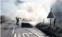  ??  ?? A firefighte­r tackles the car blaze on Macclesfie­ld Road near Kettleshul­me