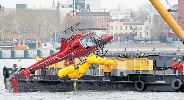  ?? AP ?? Rescate. El helicópter­o Eurocopter AS350, ayer, al ser retirado del East River. Según el piloto, la valija de un pasajero habría activado un botón que corta el suministro de combustibl­e.
