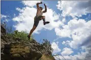  ??  ?? Adam Mitchell of Rock-About Climbing Adventures leaps off a cliff over Lake Travis in Spicewood.