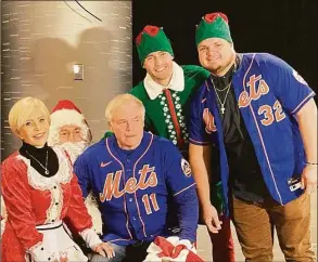  ?? Ron Blum / Associated Press ?? From left to right: Angela Showalter, wife of New York Mets manager Buck Showalter; Todd Zeile as Santa Claus; manager Buck Showalter; center fielder Brandon Nimmo as an elf; and designated hitter Daniel Vogelbach at the Mets holiday party at Citi Field in New York on Thursday.