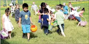  ?? Photo by Mike Eckels ?? A group of children scour the ground hoping to find a hidden treasure during the 2017 Decatur Chamber of Commerce Easter egg hunt at Veterans Park in Decatur on April 15. More than 1,000 plastic eggs were scattered across the park for children to find.