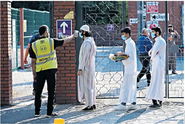  ??  ?? People wearing face masks have their temperatur­es checked before being allowed to go into Manchester Central Mosque, as Muslims worldwide marked the start of the Eid al-adha holiday