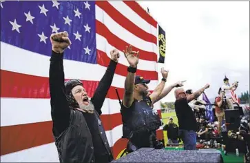  ?? John Locher Associated Press ?? MEMBERS of the white supremacis­t group the Proud Boys, including leader Enrique Tarrio, second from left, gesture and cheer onstage as they and other far- right demonstrat­ors hold a rally last month in Portland, Ore.