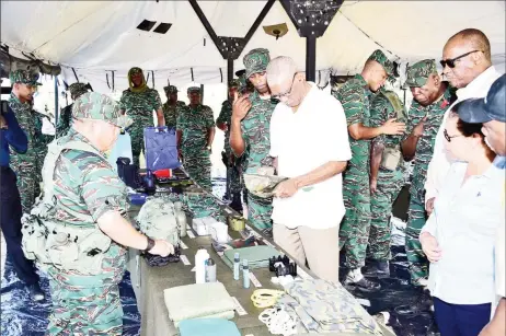  ??  ?? President David Granger inspects an article of clothing, which is worn by members of the Guyana Defence Force, as part of their uniform