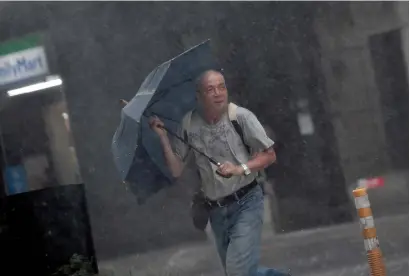  ?? AFP ?? A man walks during a storm in Xindian district, New Taipei City, as Typhoon Megi hit eastern Taiwan on Tuesday. Taiwan went into shutdown on Tuesday as the island faces its third typhoon in two weeks. —