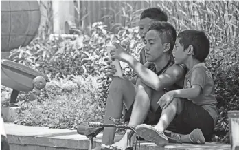  ?? MACKY LIM ?? DIGITAL ERA. Young boys park their bikes at the side of the road as they play games on their tablet at the Davao City Hall.