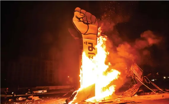  ?? AFP ?? The ‘Revolution fist,’ symbol of Lebanon’s October 2019 uprising, burns after it was set on fire by supporters of former Prime Minister Saad Hariri, in Beirut’s central Martyr’s Square, on Wednesday.