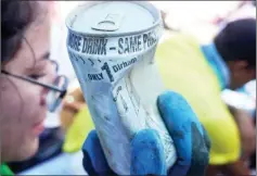  ??  ?? A volunteer shows a soda can collected from the shore.