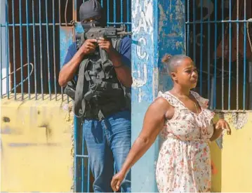  ?? ODELYN JOSEPH/AP ?? A resident walks past a National Police officer guarding the empty National Penitentia­ry after a small fire inside the jail in downtown Port-au-Prince, Haiti, on Thursday. This is the same prison that armed gangs stormed late March 2 and hundreds of inmates escaped.