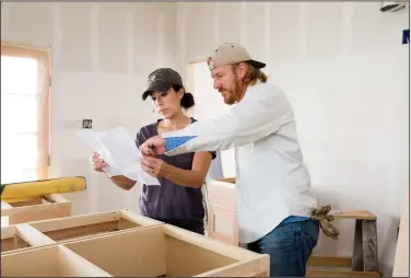  ??  ?? Chip and Joanna Gaines discuss cabinets while working on a house. The Gaines’ home design work seems to divide along traditiona­l male and female lines, but Joanna is the driving force behind the brand.