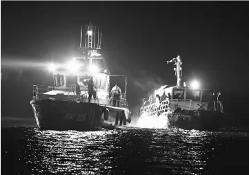  ?? — AFP photo ?? A border police ship (left) draws a migrants transporti­ng vessel to Midia Port at Black Sea coast next to Navodari city.