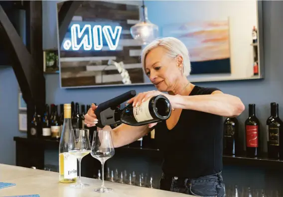  ?? LAURA MORTON ?? Sommelier Natasha Zeligs pours a glass of wine for a customer at Vin Wine Bar + Bottle Boutique, located at The Crossroads Carmel.