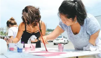  ?? STAFF PHOTO BY ROBIN RUDD ?? Alma Estrada. left. and Emily Godoy work on one of three mural sections. Artist Alex Paul Loza hosted a mural painting project at ArtsBuild by the Latino Community on Sunday.