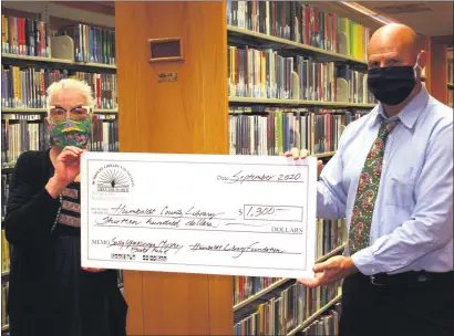  ?? PHOTOS BY COURTESY OF THE HUMBOLDT LIBRARY FOUNDATION ?? Humboldt Library Foundation member Kathy Murphy presents $1,300 from the Sally Upatisring­a Mystery Fund to Humboldt County Acting Director Chris Cooper.