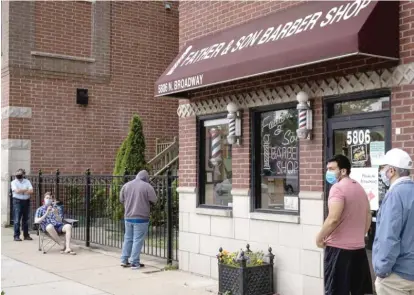  ?? ASHLEE REZIN GARCIA/SUN-TIMES ?? Andrew Carpenter brought a chair to wait in line Wednesday at Father & Son Barber Shop in Edgewater.