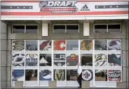  ?? G-JUN YAM — THE ASSOCIATED PRESS ?? A man passes a United Center entrance with NHL team logos as preparatio­n for the NHL Draft continue in Chicago.