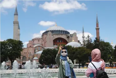  ?? (Ayman Sahely/File Photo/Reuters) (Murad Sezer/Reuters) ?? Right: TROOPS LOYAL to Libya’s internatio­nally recognized government prepare equipment, in Tripoli, Libya, on July 6.
POSING FOR a selfie in front of Hagia Sophia in Istanbul, Turkey, on July 11.