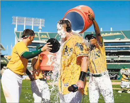  ?? JANE TYSKA — STAFF PHOTOGRAPH­ER ?? A’s hero Mark Canha (20) is doused with liquid and hit with a cream pie after hitting a walk-off home run Wednesday at the Coliseum.