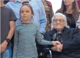  ?? PATTY NIEBERG /ASSOCIATRD PRESS ?? Melpomeni Dina, 92, a resident of Greece, holds the hand of an Israeli girl during a reunion Sunday with members of a family she rescued during World War II.