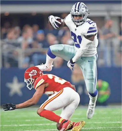  ??  ?? Cowboys running back Ezekiel Elliott (21) leaps over the Chiefs’ Marcus Peters on Sunday. TIM HEITMAN/USA TODAY SPORTS