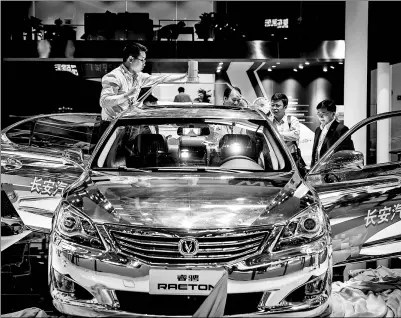  ?? BLOOMBERG ?? A self-driving car manufactur­ed by Chongqing Changan Automobile Co, a modified version of its Raeton sedan, stands on display as a technician fixes a sensor onto its roof at the Beijing Internatio­nal Automotive Exhibition in Beijing in April.