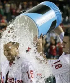  ?? TOM MIHALEK — THE ASSOCIATED PRESS ?? The Phillies’ Ty Kelly gets doused with water by teammate Tommy Joseph after driving in the winning run with a single during the 11th inning against the Atlanta Braves Saturday at Citizens Bank Park. The Phillies won 4-3.