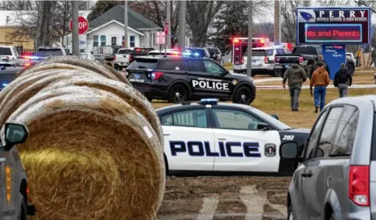  ?? ANDREW HARNIK/ASSOCIATED PRESS ?? Above, police responded to Perry High School in Perry, Iowa, on Thursday, after a shooting there. At left, children were led away from the middle and high school complex.