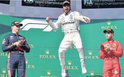  ?? AFP ?? Hungarian Grand Prix champion Lewis Hamilton of Mercedes, centre, celebrates on the podium as Red Bull’s Max Verstappen, left, and Ferrari’s Sebastian Vettel look on.