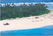  ?? Australian Defence Force ?? An Australian army helicopter lands on the beach where three mariners wrote their plea for help.