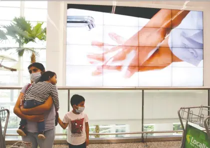  ?? SANTIAGO ARCOS/REUTERS ?? A woman and her son wear protective face masks while standing near a screen showing the handwashin­g steps, as part of the security measures due to the outbreak of COVID-19, at Jose Joaquin de Olmedo Internatio­nal Airport in Guayaquil, Ecuador on Friday.