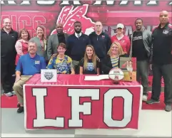  ?? / Scott Herpst ?? LFO senior basketball player Macey Gregg (seated, second from right) signed her letter of intent to play for the University of North Georgia this past Thursday. On hand for the ceremony at LFO High School were Lanham Gregg, Cameron Gregg and Allison Gregg, On the back row were LFO assistant coach Matt Culbreth, LFO volleyball coach Diane Norwood, LFO assistant coach Keri Miller, Ken Smith, Chris Collins, Bryon Veal, LFO assistant coach Krista Davis, Juan Hansford and LFO head coach Dewayne Watkins.