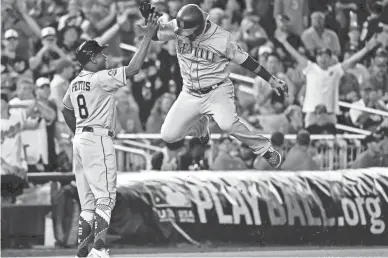  ??  ?? American League infielder Jean Segura of the Seattle Mariners celebrates with American League third base coach Gary Pettis of the Houston Astros after hitting a three-run home run during the eighth inning against the National League in the MLB All Star Game on Tuesday.