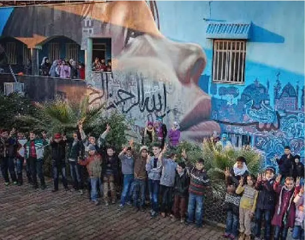  ??  ?? Students celebrate the new mural painted on the wall of Al Salam by artists with the Karam Foundation’s Zeitouna program.