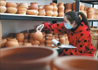  ?? LUO GUOYANG / FOR CHINA DAILY ?? TANG KE / FOR CHINA DAILY
Left: An employee from a Longyao clay pottery workshop in Pengzhou, Sichuan province, checks the items. The heritage workshop resumed production in March.