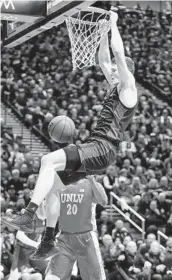  ??  ?? SDSU forward Yanni Wetzell hangs on the rim after a dunk against UNLV on Saturday.