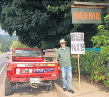  ?? Hailey Branson-Potts Los Angeles Times ?? WAYNE CARTWRIGHT, 70, stands with his homemade Bernie Sanders sign and his pickup truck covered in progressiv­e-themed bumper stickers outside his house in rural Quincy in right-leaning Plumas County.