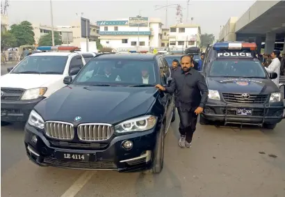  ?? AFP ?? Security personnel escort a vehicle carrying ousted prime minister Nawaz Sharif as he leaves the Rawal Lounge of Benazir Bhutto Internatio­nal airport upon his arrival from London in Islamabad on Thursday. —