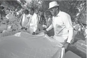  ??  ?? Morris Robinson spreads a tablecloth at the Le Dîner en Blanc event. The picnic has taken place in more than 70 cities.