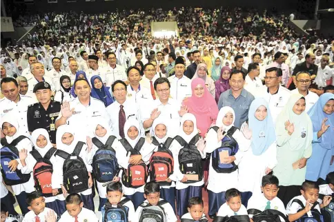  ??  ?? Shafie (third row, fifth from right) with his wife Shuryani, Jaujan (third from right), other leaders and the recipients in the back to school program at the Semporna Community Hall.