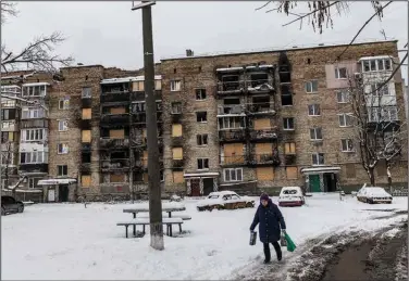  ?? (The New York Times/David Guttenfeld­er) ?? A Ukrainian woman walks through her apartment block in Irpin, Ukraine, on Wednesday. The town was heavily damaged in the early weeks of the war. Now, in Irpin and across Ukraine, civilians are bracing for the brutal winter months while enduring electricit­y shortages caused by Russian attacks on infrastruc­ture.