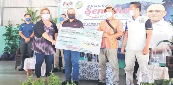  ?? ). ?? Lilian (le ) with the representa­tive from the farming community in Kampung Tabiu Telupid receiving the Kebuniti program funding from Dr Ronald (second le