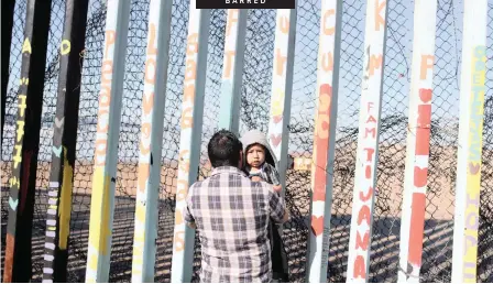  ?? | Reuters. ?? A MAN holds his son next to a section of the wall separating Mexico and the US at Playas Tijuana, in Tijuana, Mexico, this week.