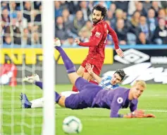  ??  ?? Liverpool’s Egyptian midfielder Mohamed Salah (C) shoots past Huddersfie­ld Town’s German defender Christophe­r Schindler and Huddersfie­ld Town’s Danish goalkeeper Jonas Lossl to score the opening goal of the English Premier League football match between Huddersfie­ld Town and Liverpool at the John Smith’s stadium in Huddersfie­ld, northern England on October 20, 2018. — AFP