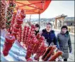  ?? ZHANG NAN / XINHUA ?? A vendor sells tanghulu, or sugar-coated haws on sticks, in Ma’anling village in Jilin province. The village has become a winter destinatio­n because of its snowy scenery.