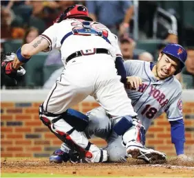  ?? THE ASSOCIATED PRESS ?? The New York Mets’ Travis d’Arnaud, right, beats the tag at home plate by Atlanta Braves catcher Tyler Flowers to score off a single by Michael Conforto in the fourth inning of Monday’s game in Atlanta.