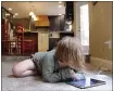  ?? SARA CLINE — THE ASSOCIATED PRESS ?? Lizzie Dale sprawls on the floor to play games on an iPad as her siblings work on school work in their home in Lake Oswego, Ore.